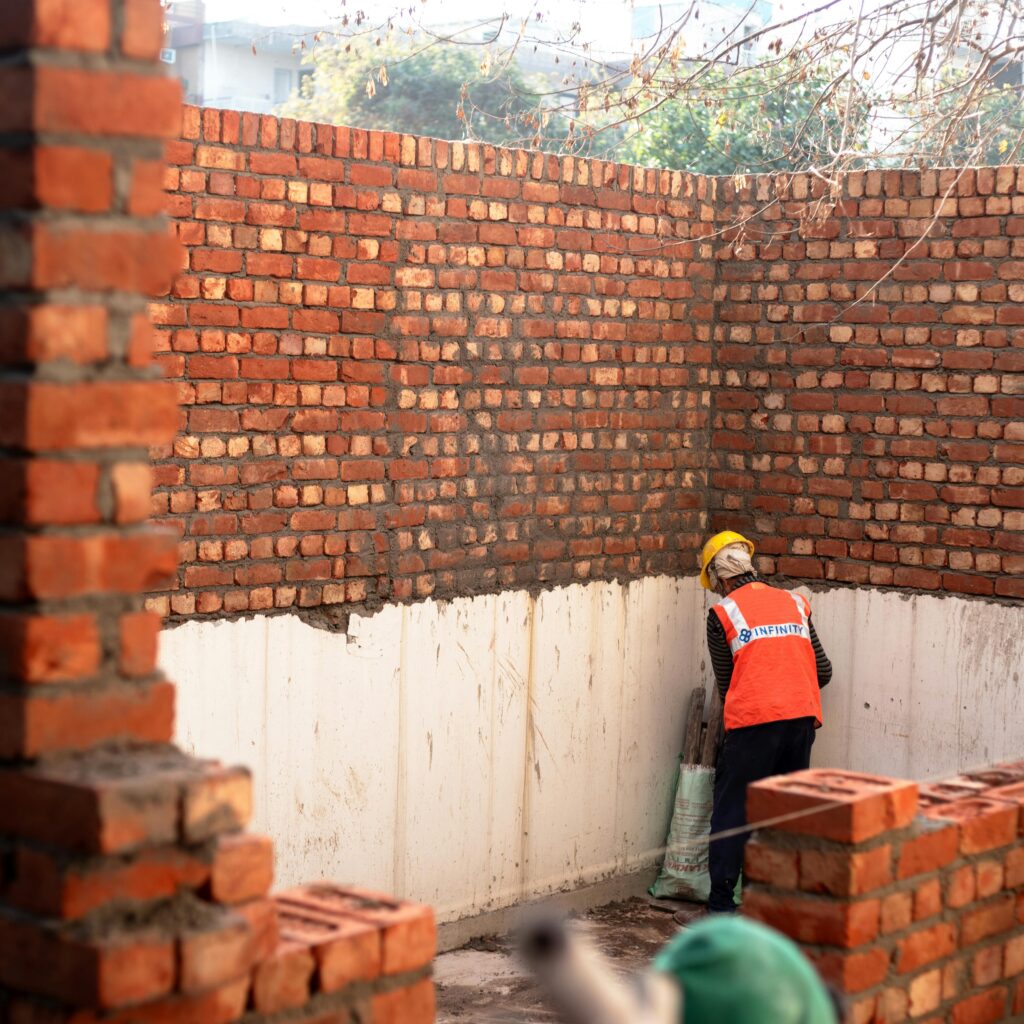 A construction worker layering bricks on a site in Delhi, India.